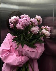 a woman with pink flowers wrapped around her body in front of an elevator door,