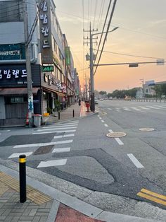 an empty city street at sunset with buildings in the background