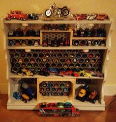 toy cars and trucks are sitting on top of a bookcase that is filled with toys