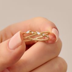 a woman's hand holding a gold ring with diamonds