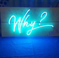 a neon sign with the word why? on it is lit up against a blue background