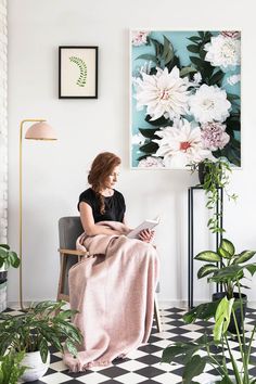 a woman sitting in a chair with a blanket on her lap looking at a magazine