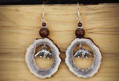 Each pair of these earrings are unique as they come from real Montana elk antlers. Elk she their antlers yearly. A small silver bear hangs in the middle of the antler frame. On top of the antler pieces are round brown beads, small silver spacers, smaller brown bead, on top. Dimensions: The earrings hang 2" below the sterling silver ear wires and the antler pieces are 1 1/4" across. Comes in a natural brown gift box wrapped in raffia. Is this a Gift? We would be happy to place a gift card. At Che Antler Tip Earrings, Antler Beaded Earrings, Antler Earrings Handmade, Antler Bracelet, Antler Rings, Antler Beads, Deer Antler Crafts, Deer Antler Jewelry, Turkey Jewelry