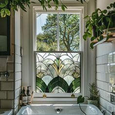 a bath tub sitting under a window next to a green leafy plant in a bathroom