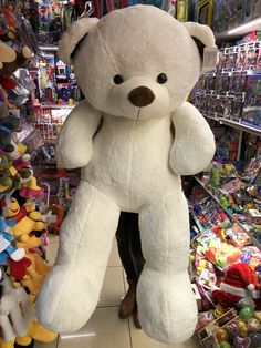 a large white teddy bear sitting in the middle of a store aisle filled with toys