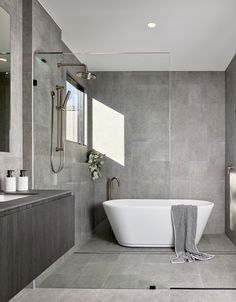 a bathroom with a bathtub, sink and shower in grey tile flooring next to a large window