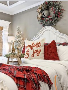 a bedroom decorated for christmas with white bedding and red throw pillows on the headboard