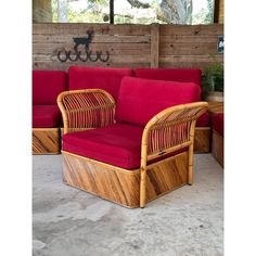 a red couch sitting on top of a cement floor next to a wooden table and chair