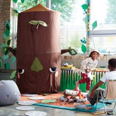 two children are sitting in front of a giant paper cut out of a tree trunk