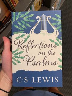 a person holding up a book about reflections on the pastams in front of bookshelves