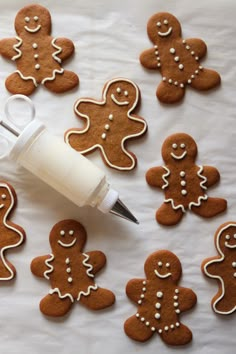 a table topped with lots of cut out ginger cookies next to a bottle of glue