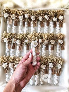 a hand holding an item in front of a white wall with flowers and ribbons on it