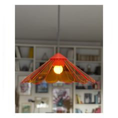 an orange light hanging from the ceiling in a room with bookshelves behind it