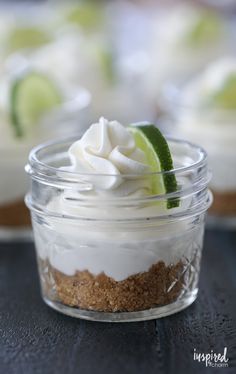 a small glass jar filled with whipped cream and limes on top of a table