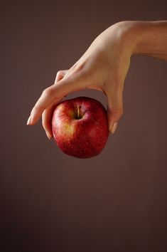 a person holding an apple in their right hand and reaching for it with both hands