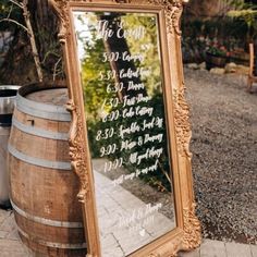 a large mirror sitting on top of a wooden barrel next to a sign that says the wedding date