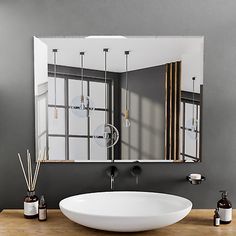 a bathroom sink sitting under a mirror on top of a wooden counter next to a window