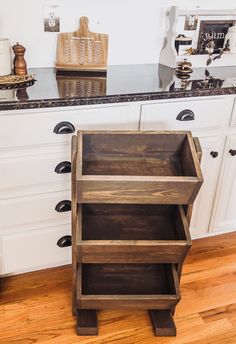 a kitchen with white cabinets and black counter tops is pictured in this image, there are wooden crates stacked on top of each other