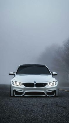 the front end of a white car on a foggy road