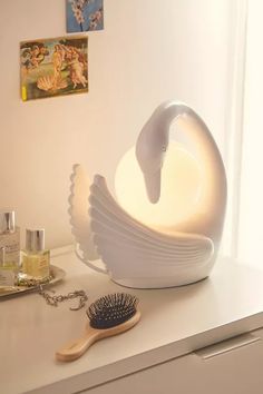 a white swan shaped bowl sitting on top of a counter next to a brush and other items