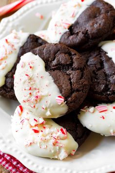 chocolate cookies with white frosting and candy canes on a red and white plate