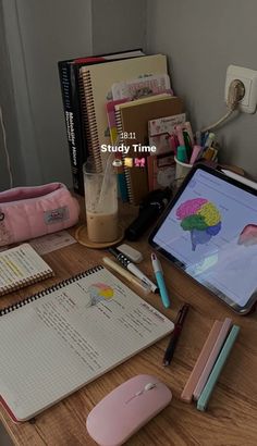 a laptop computer sitting on top of a wooden desk next to a mouse and books