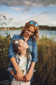 a mother and her daughter standing in front of a body of water