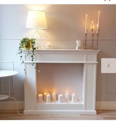 a white fireplace with lit candles in it