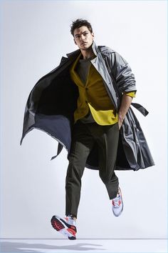 a man in black jacket and yellow shirt is jumping with his coat over his head