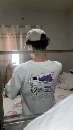 a woman standing in front of a mirror wearing a white t - shirt and cap