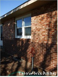 a red brick house with white windows and a hose attached to the side of it