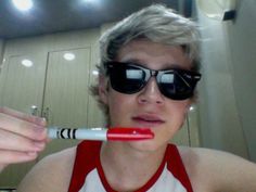 a person with sunglasses on brushing their teeth