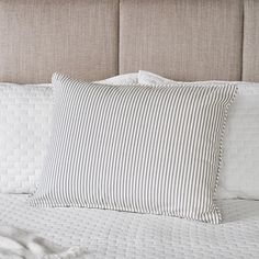 a close up of a bed with pillows and blankets on top of the headboard