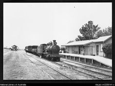 black and white photograph of an old train on the tracks in front of a building