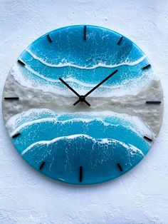 a blue and white wall clock with waves on the beach in front of an ocean