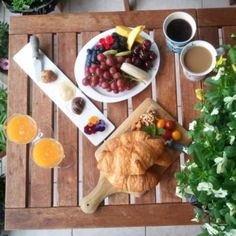 a wooden table topped with plates of food next to cups of coffee and orange juice