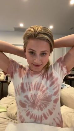 a woman with her hands behind her head posing for the camera in front of a bed