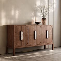 a wooden cabinet sitting in front of a window next to a vase on top of a table