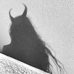 the shadow of a woman's head is cast on a wall with long hair