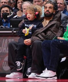 a man sitting next to a little boy at a basketball game