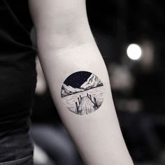 a woman's arm with a tattoo on it that has mountains in the background