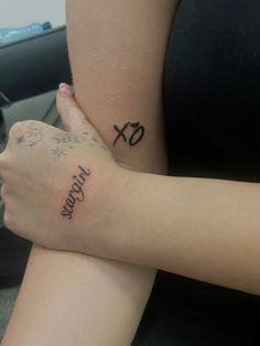 two people with tattoos on their arms sitting next to each other