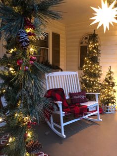 a white rocking chair sitting on top of a porch covered in christmas trees and presents