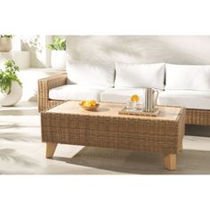 a wicker coffee table sitting on top of a white floor next to a couch