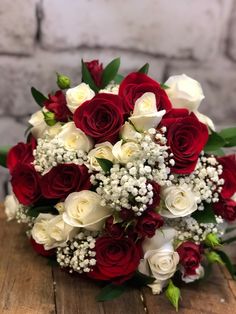 a bouquet of red and white roses on a wooden table