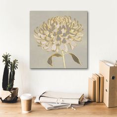 a white and gold flower sitting on top of a wooden table next to some books