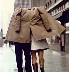 a man and woman walking down the street holding an umbrella