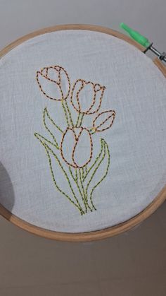 a close up of a embroidery on a hoop with flowers in the middle and thread