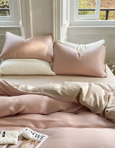 a bed with pink sheets and pillows on it