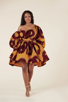 a woman in an african print dress poses for the camera with her hands on her hips